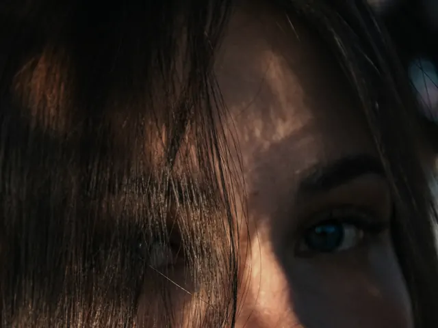 Rosto de uma mulher parcialmente coberto pelo cabelo, em luz quente