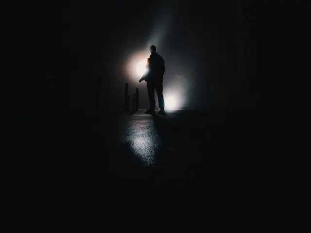 Silhueta de uma pessoa em uma rua escura, contra uma luz difusa